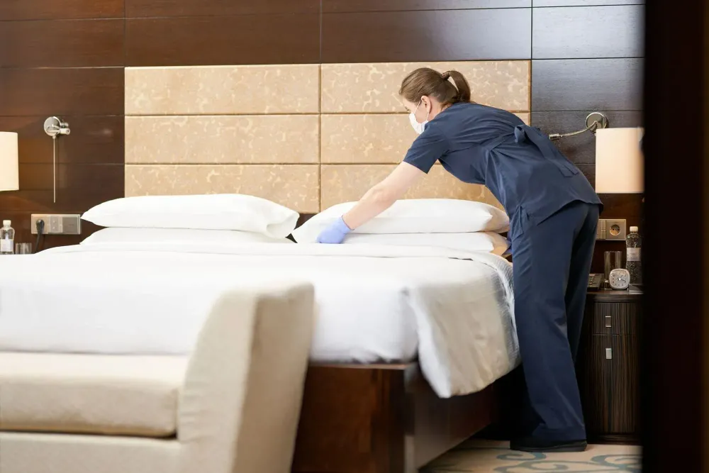 Housekeeper wearing a mask in hotel room.